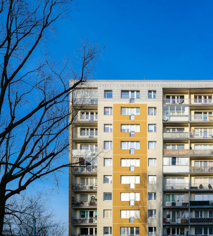 Urban residential building in Gdańsk against a clear blue sky with a bare tree.