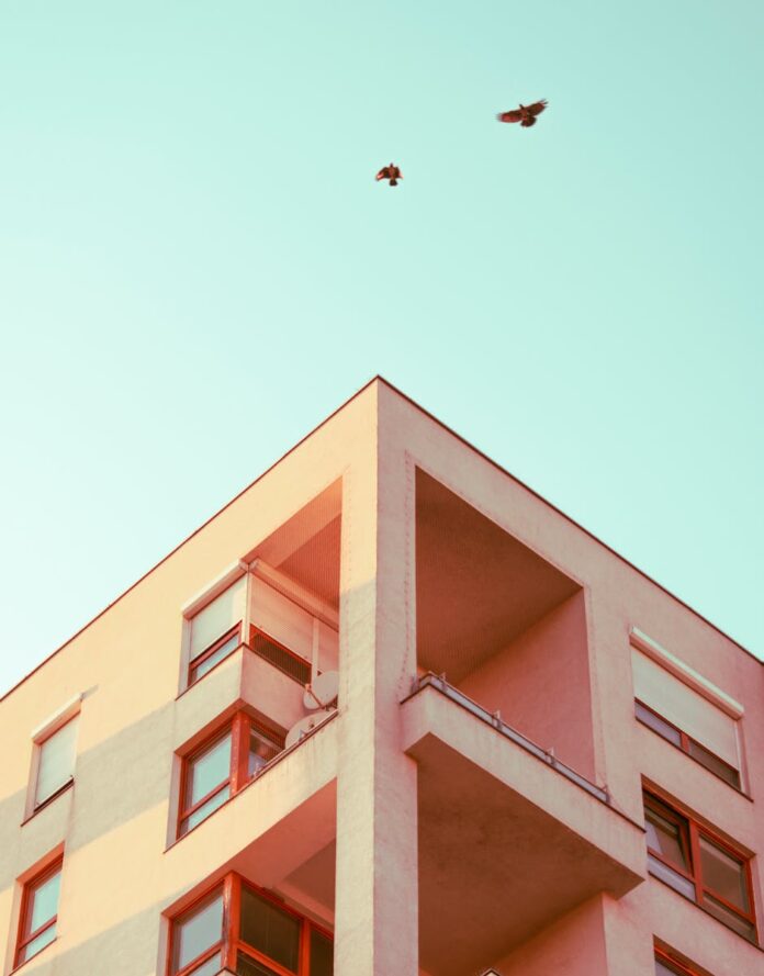 Low-angle view of a modern building facade with birds flying above in Warsaw.